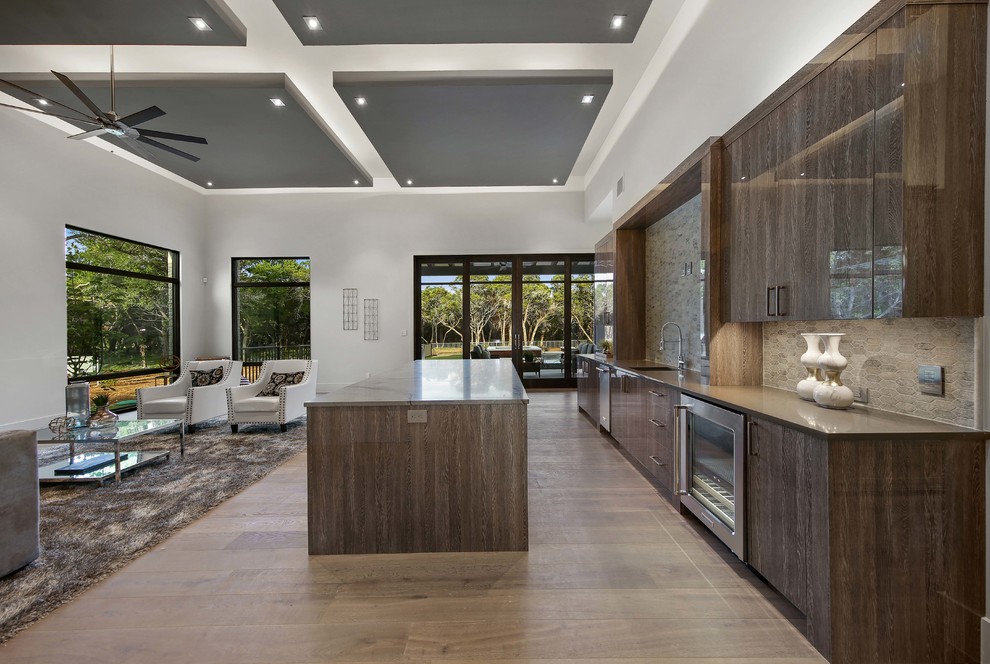 This is an example of a contemporary single-wall wet bar in Austin with an undermount sink, flat-panel cabinets, dark wood cabinets, solid surface benchtops, grey splashback, stone tile splashback, light hardwood floors and grey floor.