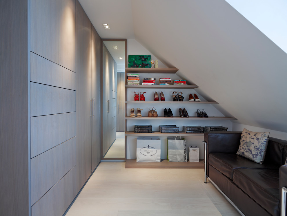 This is an example of a dressing room in London with flat-panel cabinets, grey cabinets and light hardwood floors.