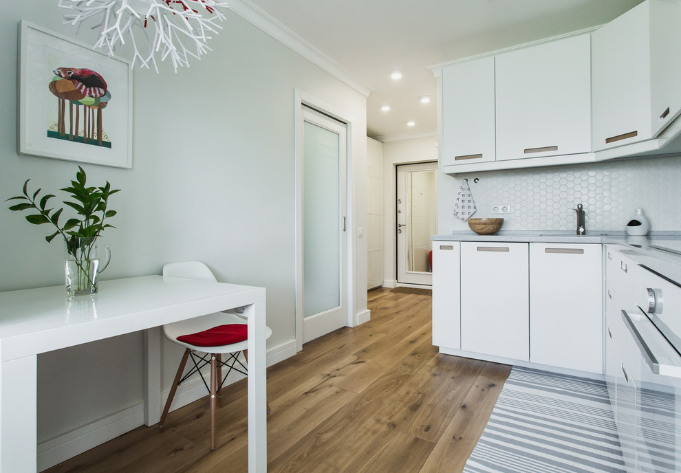 Contemporary l-shaped eat-in kitchen in Moscow with flat-panel cabinets, white cabinets, white splashback, white appliances, medium hardwood floors and no island.