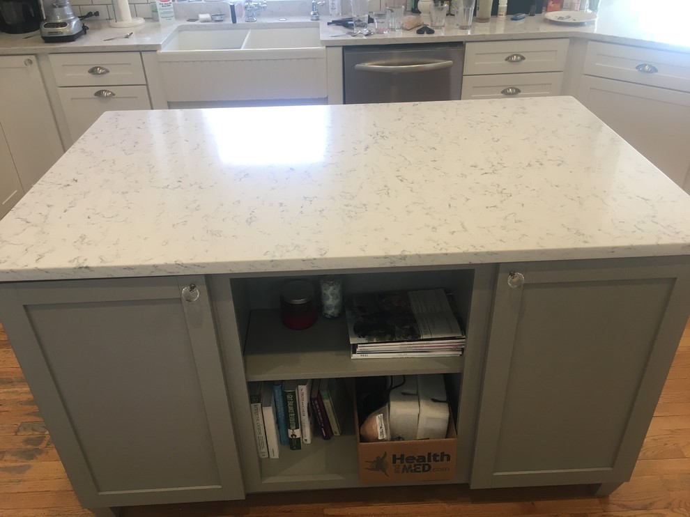 Inspiration for a large transitional l-shaped medium tone wood floor and brown floor open concept kitchen remodel in Omaha with a farmhouse sink, shaker cabinets, white cabinets, quartz countertops, white backsplash, ceramic backsplash, stainless steel appliances, two islands and white countertops