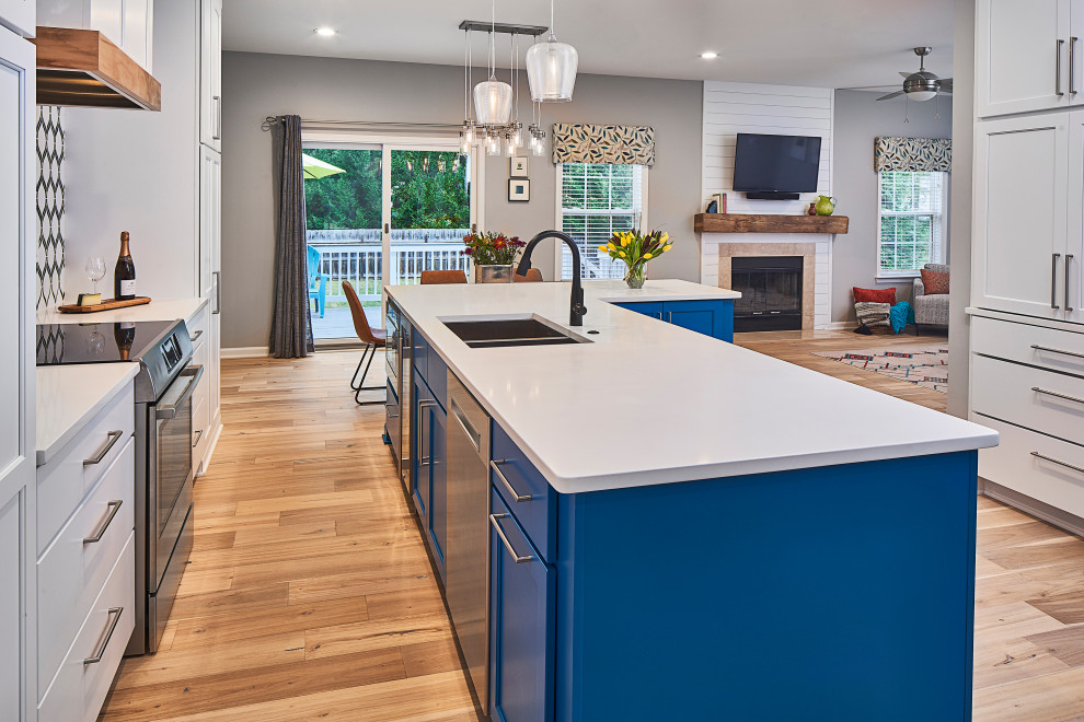 Inspiration for a mid-sized transitional eat-in kitchen in Charlotte with an undermount sink, shaker cabinets, blue cabinets, quartz benchtops, multi-coloured splashback, mosaic tile splashback, stainless steel appliances, light hardwood floors, with island, brown floor and white benchtop.