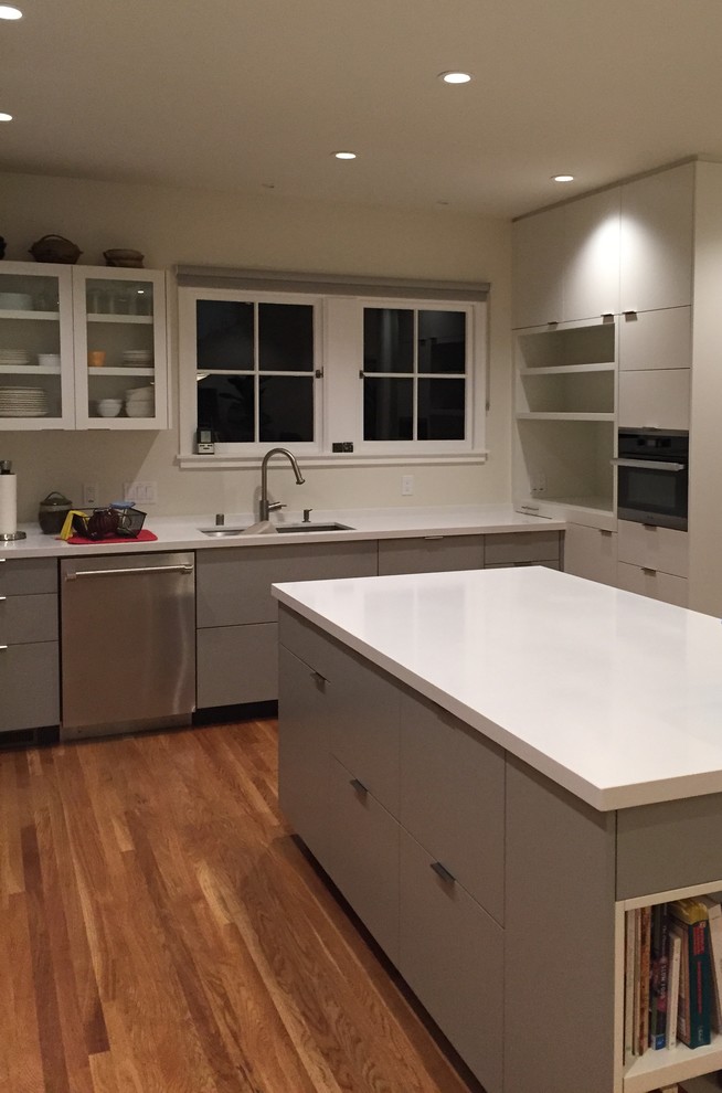 Eat-in kitchen - mid-sized u-shaped medium tone wood floor eat-in kitchen idea in Seattle with an undermount sink, flat-panel cabinets, white cabinets, quartz countertops, stainless steel appliances and an island