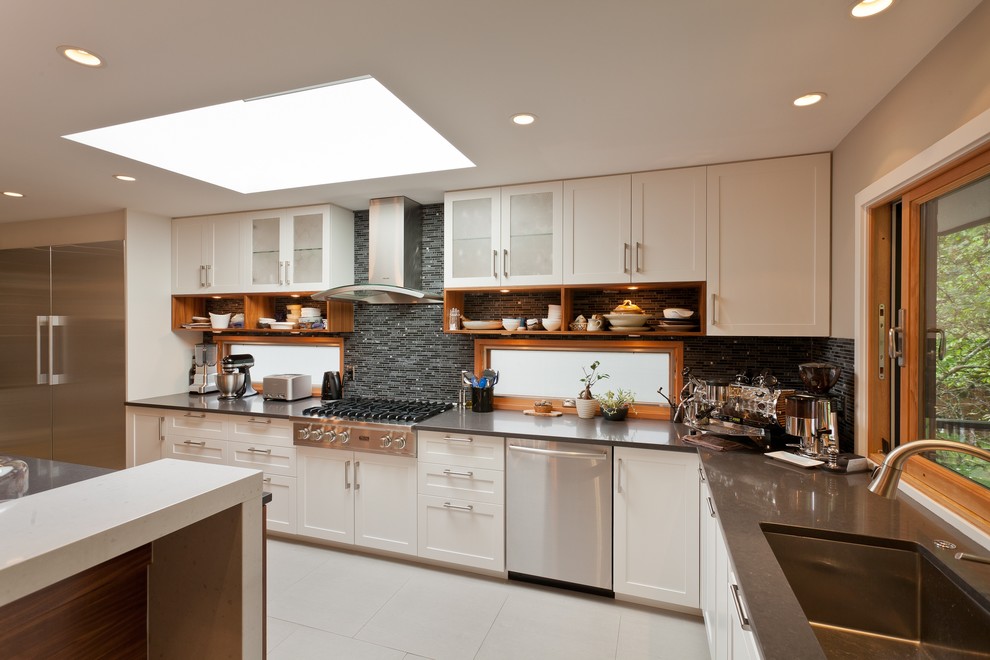 This is an example of a mid-sized contemporary l-shaped open plan kitchen in Vancouver with an undermount sink, recessed-panel cabinets, white cabinets, quartz benchtops, grey splashback, stainless steel appliances and porcelain floors.