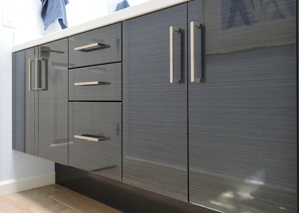 Corner shower - mid-sized contemporary 3/4 light wood floor and beige floor corner shower idea in Phoenix with flat-panel cabinets, gray cabinets, a one-piece toilet, gray walls, an undermount sink, quartz countertops and white countertops