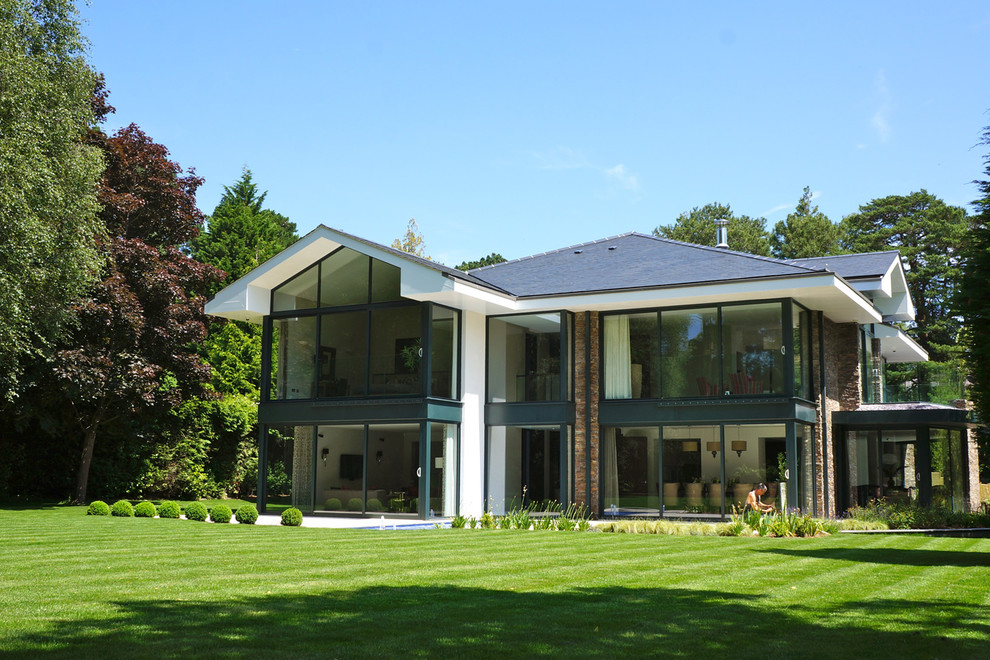Photo of a large modern two-storey white exterior in Dorset with stone veneer.