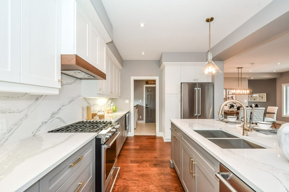 Photo of a mid-sized modern single-wall eat-in kitchen in Toronto with an undermount sink, shaker cabinets, white cabinets, quartzite benchtops, white splashback, stainless steel appliances, medium hardwood floors, with island and brown floor.