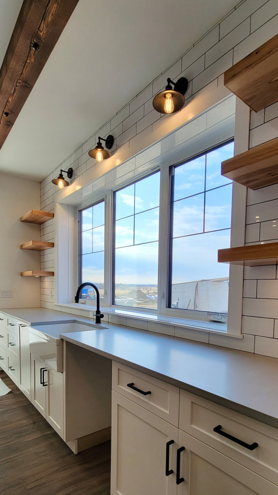 Inspiration for a large country single-wall eat-in kitchen in Edmonton with vinyl floors, brown floor, exposed beam, a farmhouse sink, beaded inset cabinets, white cabinets, quartz benchtops, white splashback, subway tile splashback, with island and grey benchtop.