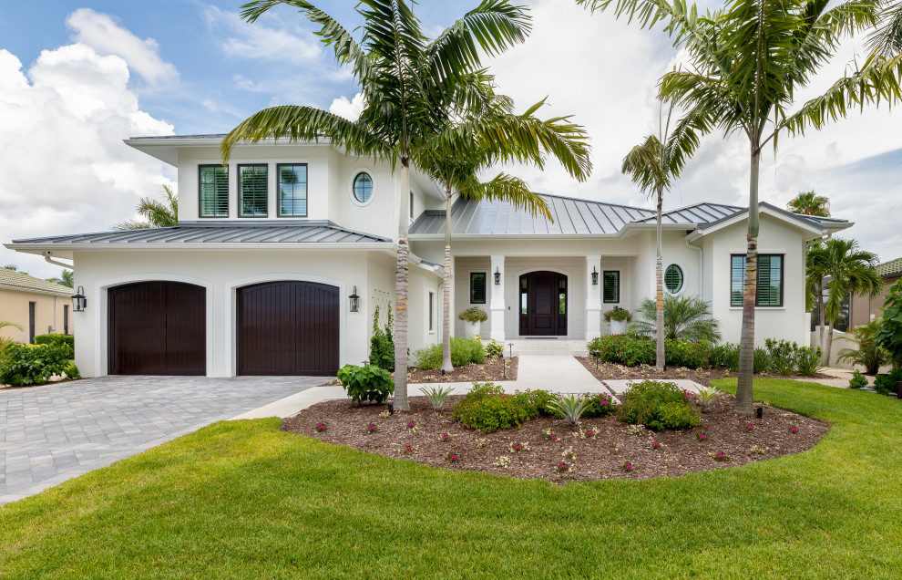 This is an example of a tropical two-storey white house exterior in Tampa with a hip roof and a metal roof.