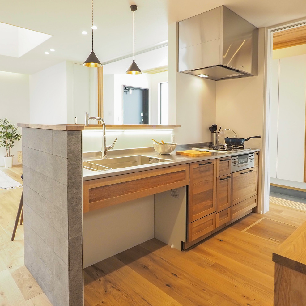 Idéer för ett mellanstort asiatiskt brun linjärt kök med öppen planlösning, med en integrerad diskho, släta luckor, skåp i mellenmörkt trä, bänkskiva i rostfritt stål, vitt stänkskydd, rostfria vitvaror, mellanmörkt trägolv och beiget golv