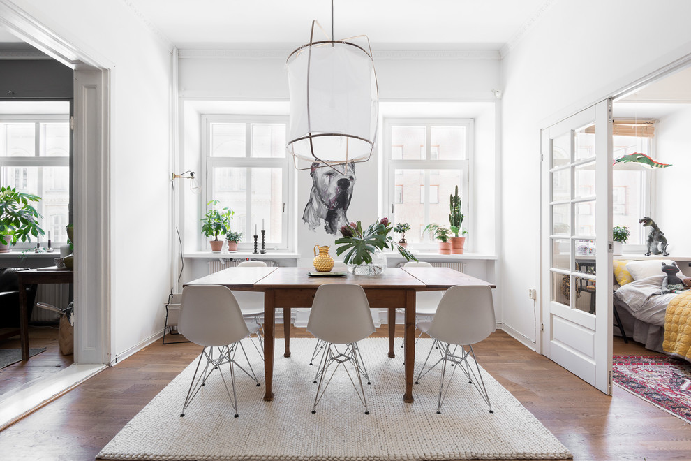 Design ideas for a mid-sized scandinavian dining room in Gothenburg with white walls, medium hardwood floors and no fireplace.