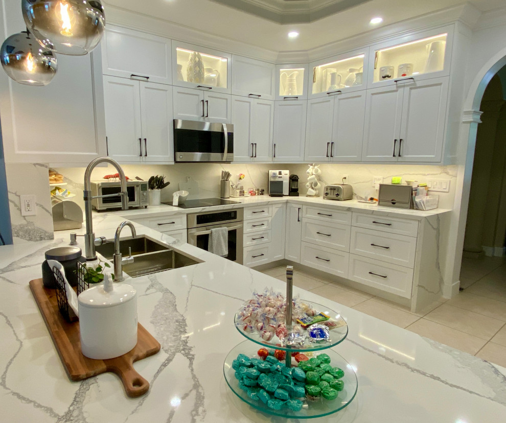 Inspiration for a transitional u-shaped porcelain tile, beige floor and coffered ceiling open concept kitchen remodel in Miami with a double-bowl sink, shaker cabinets, white cabinets, quartz countertops, white backsplash, quartz backsplash, stainless steel appliances, a peninsula and white countertops