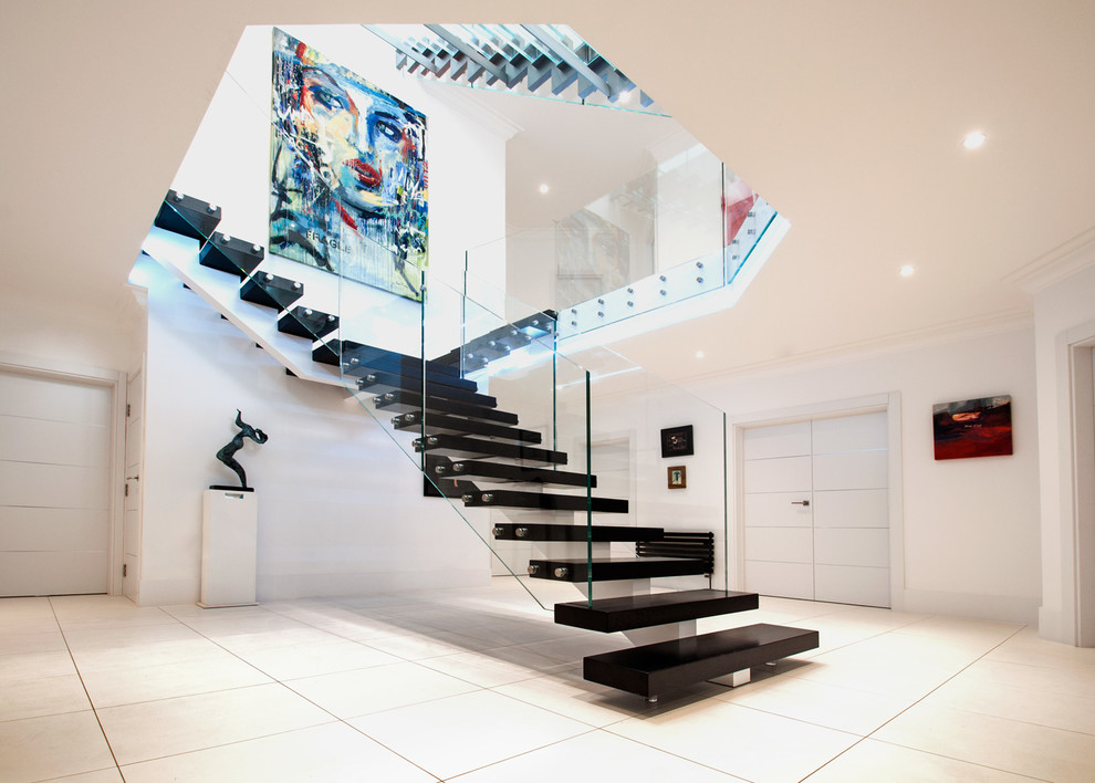 Inspiration for a large contemporary wood straight staircase in Buckinghamshire with open risers and glass railing.