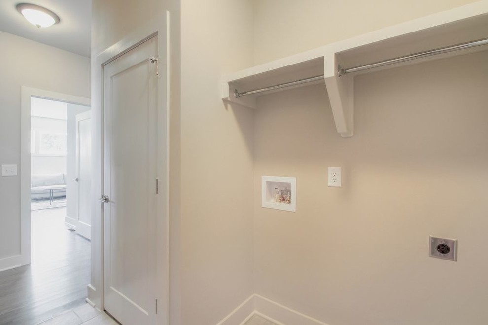 This is an example of a small contemporary single-wall laundry cupboard in Nashville with beige walls, medium hardwood floors and a side-by-side washer and dryer.