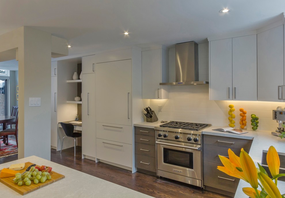 This is an example of a mid-sized contemporary u-shaped open plan kitchen in Toronto with a double-bowl sink, flat-panel cabinets, white cabinets, marble benchtops, white splashback, ceramic splashback, stainless steel appliances, dark hardwood floors, a peninsula and brown floor.