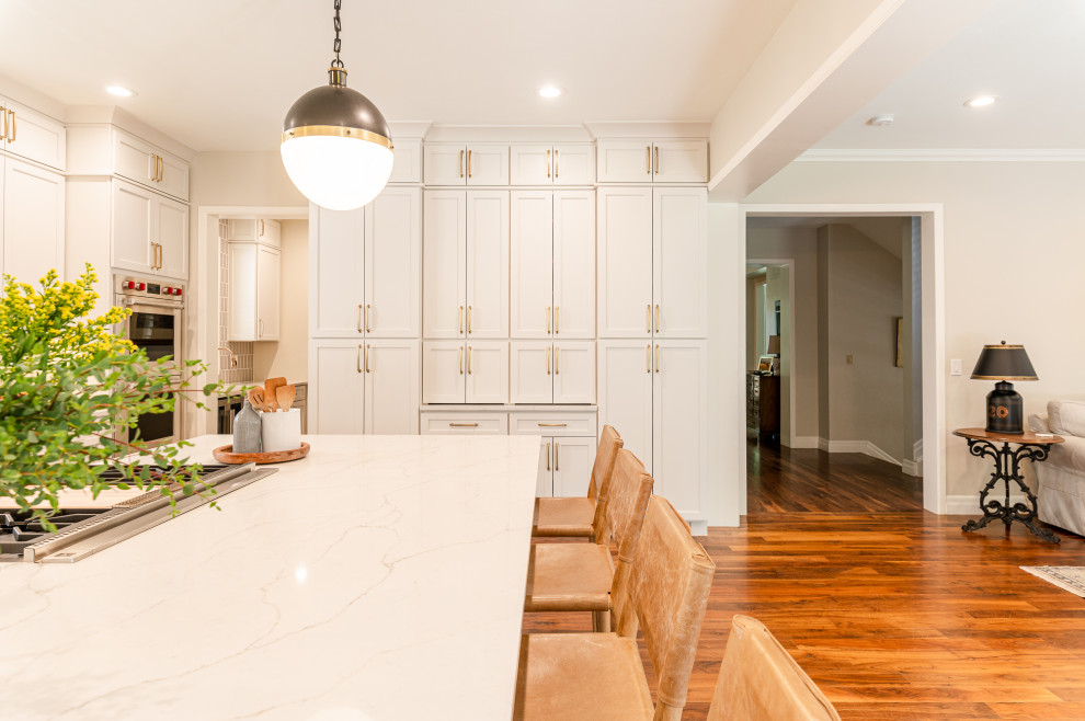 Large transitional l-shaped dark wood floor and brown floor open concept kitchen photo in Denver with a farmhouse sink, shaker cabinets, beige cabinets, quartz countertops, beige backsplash, ceramic backsplash, stainless steel appliances, an island and white countertops