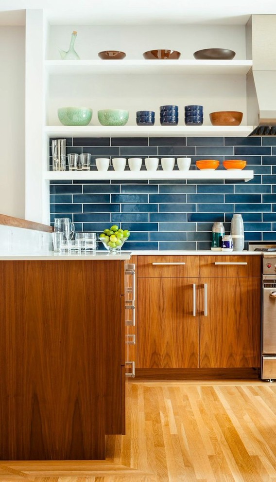 Photo of a large contemporary l-shaped eat-in kitchen in San Francisco with flat-panel cabinets, medium wood cabinets, blue splashback, stainless steel appliances, medium hardwood floors, an undermount sink, solid surface benchtops, with island, matchstick tile splashback and brown floor.