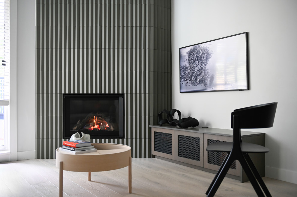 Cette image montre un petit salon minimaliste ouvert avec un bar de salon, un mur blanc, parquet clair, une cheminée d'angle, un manteau de cheminée en carrelage, un téléviseur fixé au mur et un sol blanc.
