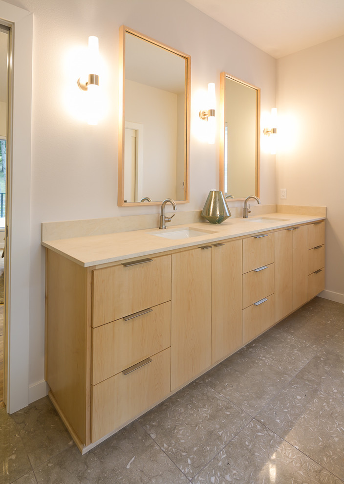Photo of a mid-sized midcentury master bathroom in Other with flat-panel cabinets, light wood cabinets, a freestanding tub, a two-piece toilet, green tile, stone tile, white walls, limestone floors, an undermount sink and limestone benchtops.