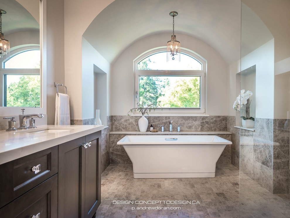 Large tuscan master gray tile and limestone tile limestone floor and gray floor bathroom photo in Vancouver with shaker cabinets, dark wood cabinets, a one-piece toilet, gray walls, an undermount sink, quartzite countertops and white countertops