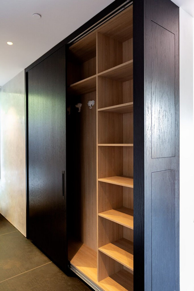 Modelo de armario vestidor unisex escandinavo grande con armarios con rebordes decorativos, puertas de armario negras, suelo de baldosas de cerámica, suelo beige y madera