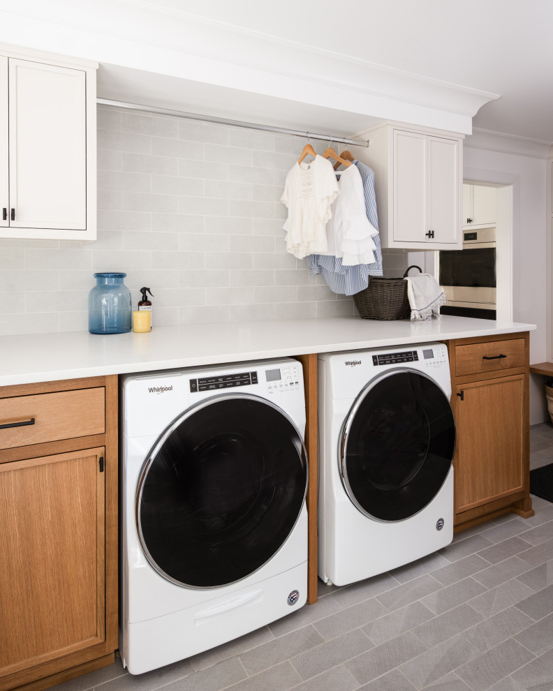 Mid-sized transitional l-shaped utility room in New York with a drop-in sink, beaded inset cabinets, white cabinets, solid surface benchtops, white walls, a side-by-side washer and dryer, grey floor and white benchtop.