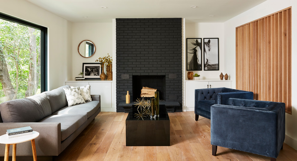 This is an example of a contemporary formal living room in Minneapolis with white walls, light hardwood floors, a standard fireplace, a brick fireplace surround and no tv.