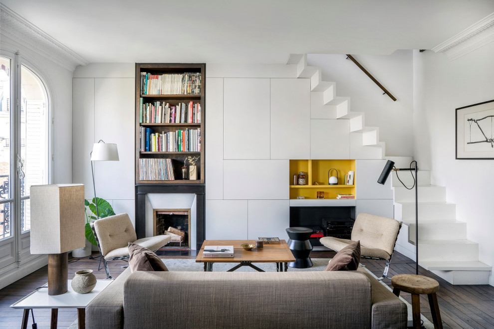 Immagine di un soggiorno classico aperto con pareti bianche, pavimento in legno massello medio, camino classico, TV nascosta, pavimento marrone e pannellatura
