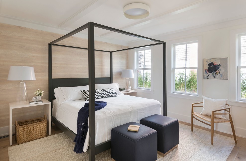 This is an example of a mid-sized beach style master bedroom in Providence with white walls, light hardwood floors, brown floor and no fireplace.