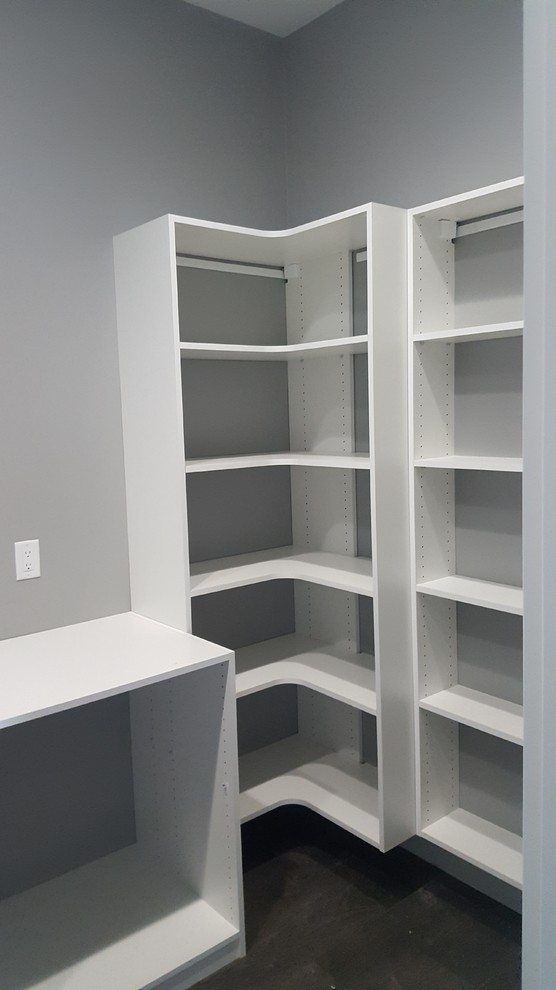 Inspiration for a mid-sized traditional gender-neutral walk-in wardrobe in Other with open cabinets, white cabinets, concrete floors and black floor.