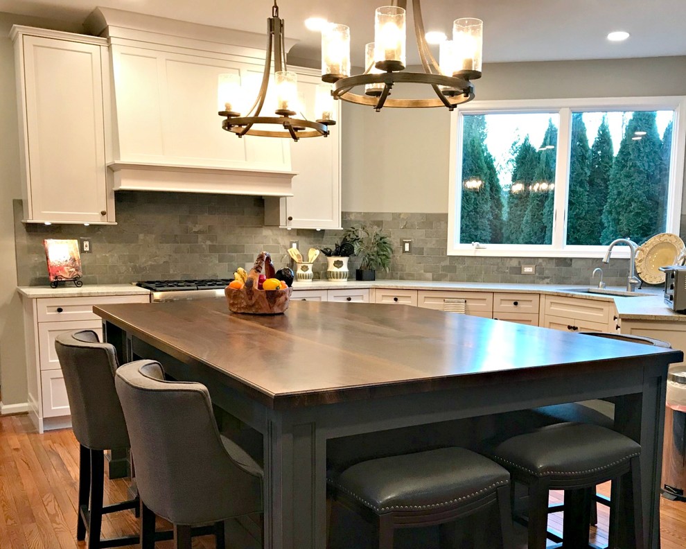 This is an example of a mid-sized transitional l-shaped eat-in kitchen in Philadelphia with an undermount sink, shaker cabinets, white cabinets, granite benchtops, grey splashback, slate splashback, medium hardwood floors, with island, brown floor and beige benchtop.