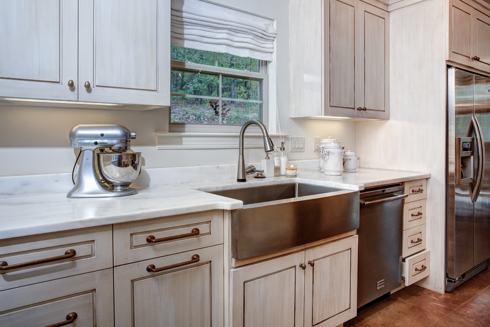 Inspiration for a large traditional l-shaped eat-in kitchen in Little Rock with a farmhouse sink, raised-panel cabinets, beige cabinets, marble benchtops, white splashback, subway tile splashback, stainless steel appliances, with island and brown floor.