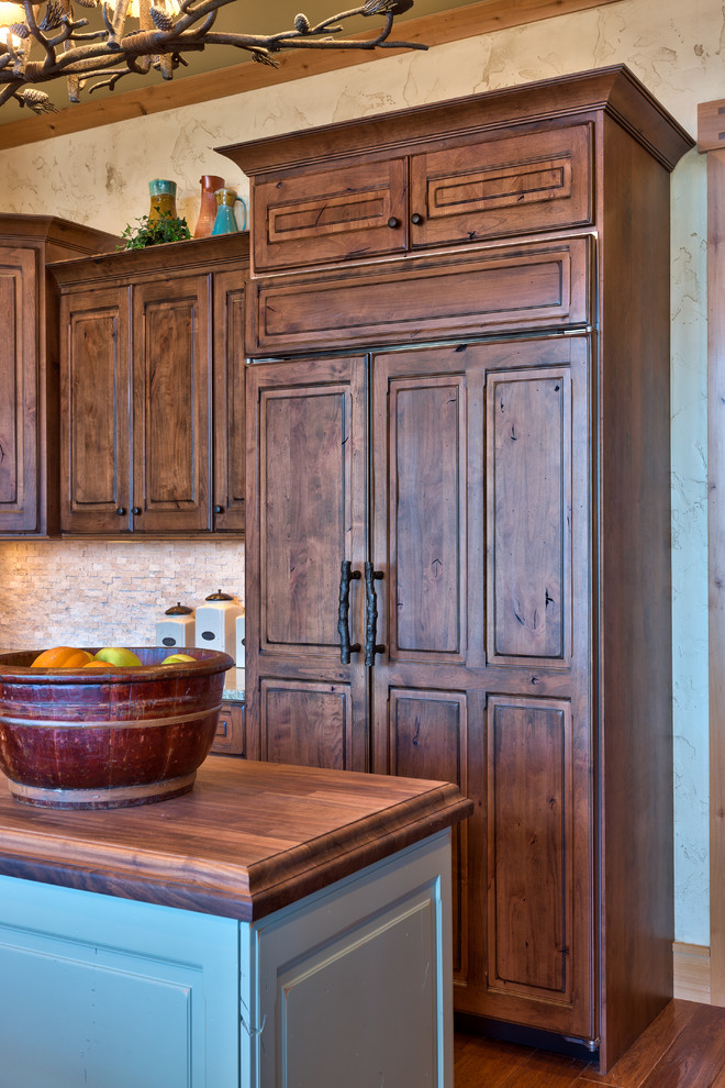 Inspiration for a rustic kitchen remodel with raised-panel cabinets, dark wood cabinets, wood countertops and paneled appliances
