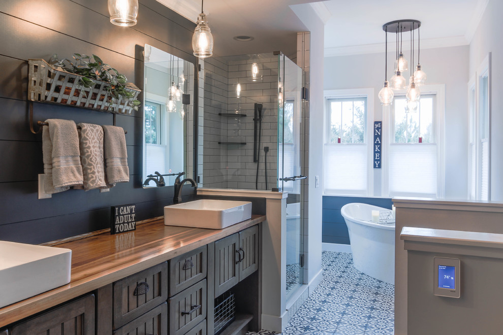 Mid-sized country master bathroom in Detroit with recessed-panel cabinets, brown cabinets, a freestanding tub, a corner shower, blue walls, mosaic tile floors, a vessel sink, wood benchtops, blue floor, a hinged shower door and brown benchtops.