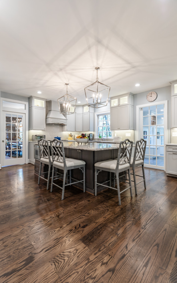 Mid-sized trendy l-shaped brown floor eat-in kitchen photo in DC Metro with a farmhouse sink, beaded inset cabinets, white cabinets, white backsplash, stainless steel appliances, an island and white countertops