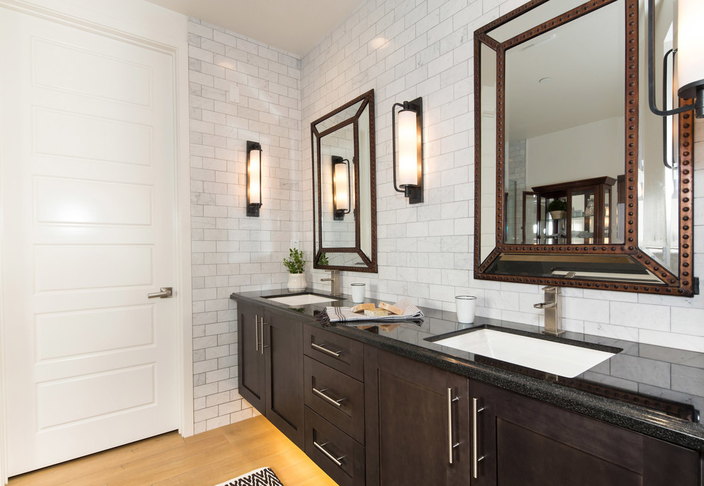 Design ideas for a mid-sized industrial master bathroom in Los Angeles with shaker cabinets, dark wood cabinets, a freestanding tub, a corner shower, a one-piece toilet, white tile, stone tile, white walls, medium hardwood floors, an undermount sink and soapstone benchtops.