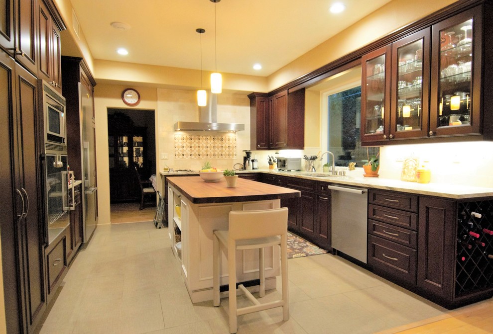 Inspiration for a mid-sized transitional l-shaped porcelain tile eat-in kitchen remodel in Orange County with an undermount sink, raised-panel cabinets, quartz countertops, stainless steel appliances, an island, dark wood cabinets and beige backsplash