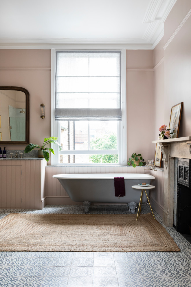 This is an example of a traditional master bathroom in London with a claw-foot tub, granite benchtops, pink walls, mosaic tile floors, an undermount sink, blue floor and flat-panel cabinets.