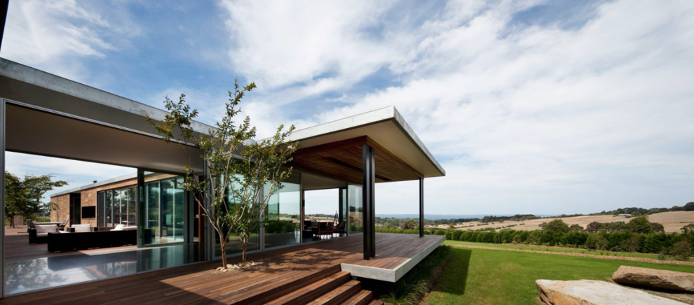 Photo of a large contemporary one-storey glass grey exterior in Melbourne with a flat roof.