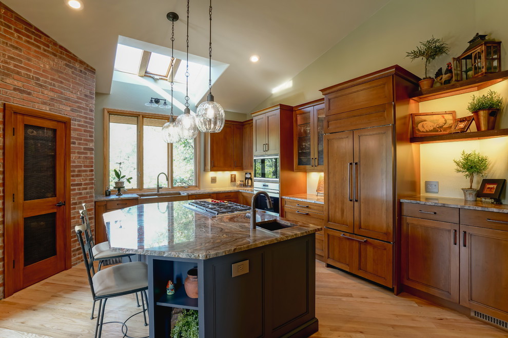 Example of a mid-sized transitional medium tone wood floor and brown floor kitchen design in Denver with a farmhouse sink, recessed-panel cabinets, medium tone wood cabinets, granite countertops, paneled appliances and an island