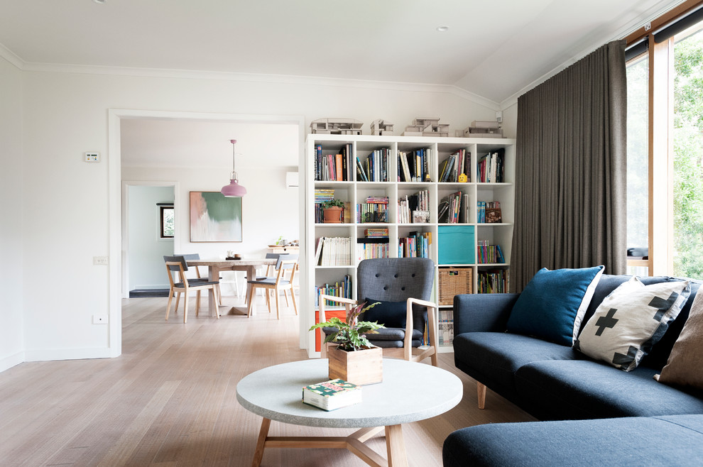 Photo of a mid-sized contemporary enclosed living room in Melbourne with a library, white walls and light hardwood floors.