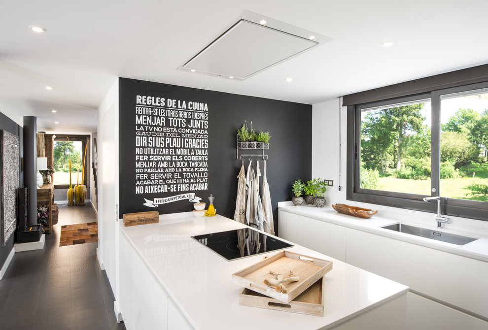 Inspiration for a large scandinavian galley kitchen in Barcelona with an undermount sink, flat-panel cabinets, white cabinets, solid surface benchtops, a peninsula, black splashback, stainless steel appliances and ceramic floors.