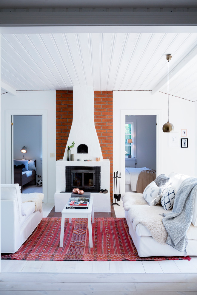 Photo of a mid-sized scandinavian formal open concept living room in Stockholm with white walls, painted wood floors, a standard fireplace and no tv.