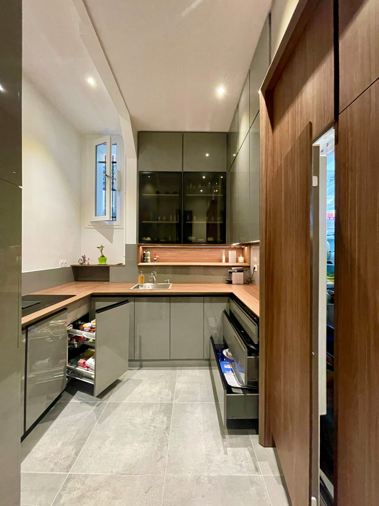 Réalisation de cuisine in U With un évier encastré, un placard à porte plane, des portes de placards vertess, un plan de travail en bois, une crédence beige, un sol en carrelage de céramique, aucun îlot, un sol gris and un plan de travail marron.