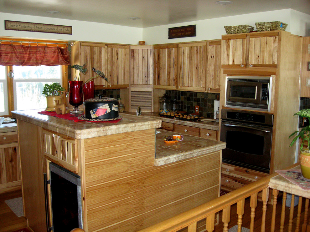 Inspiration for a mid-sized rustic u-shaped bamboo floor eat-in kitchen remodel in Seattle with an undermount sink, tile countertops, stone tile backsplash, stainless steel appliances and an island
