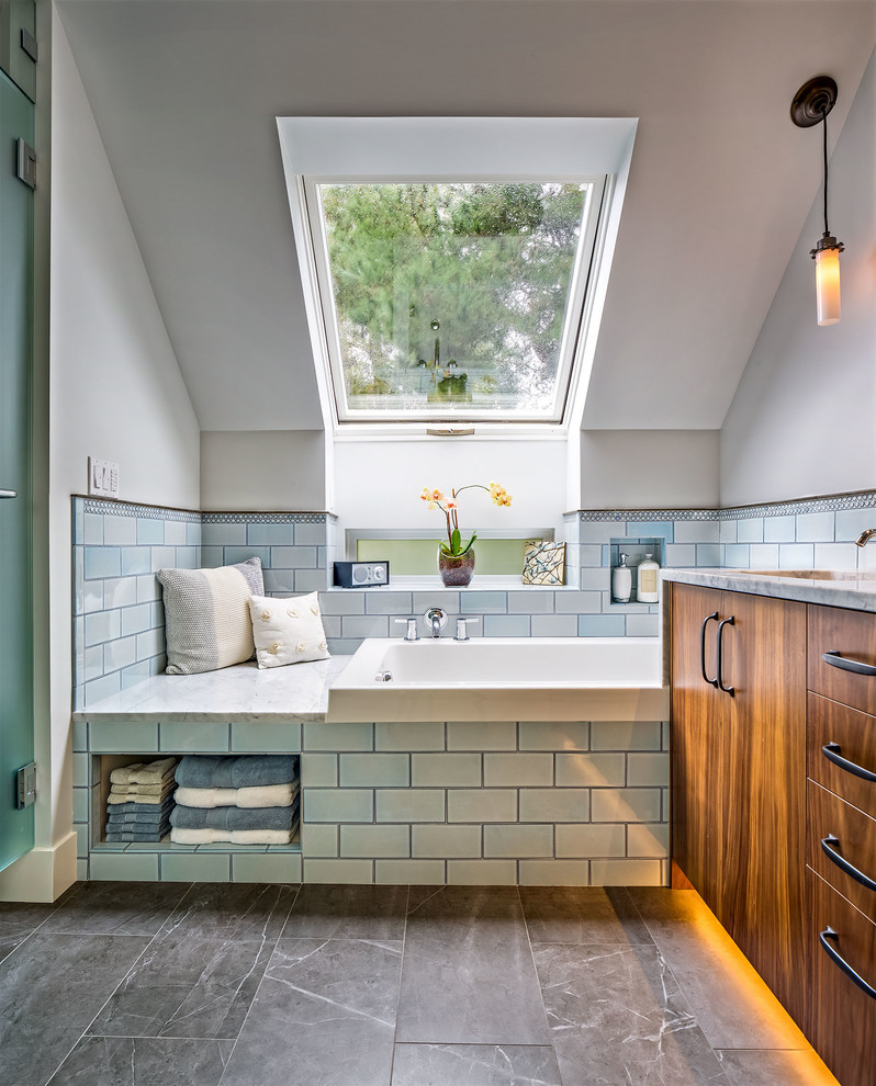 This is an example of a transitional bathroom in Seattle with flat-panel cabinets, dark wood cabinets, a drop-in tub, blue tile, subway tile and white walls.