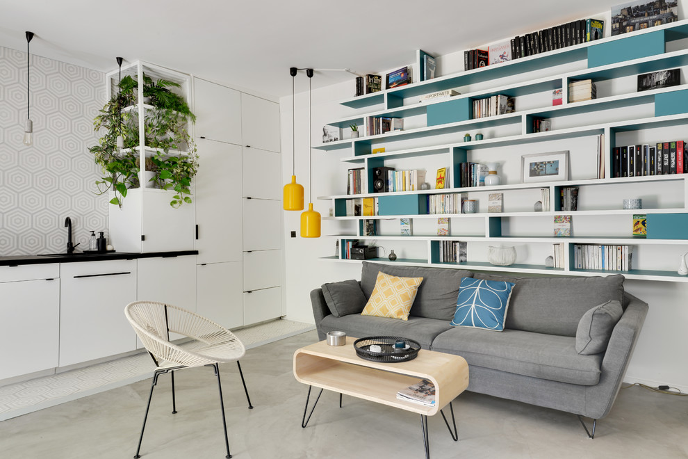 Design ideas for a mid-sized scandinavian open concept living room in Paris with a library, white walls, concrete floors, no fireplace, grey floor and a concealed tv.