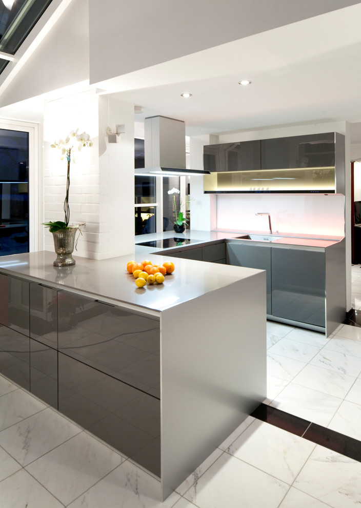 Design ideas for a large contemporary u-shaped open plan kitchen in Other with flat-panel cabinets, grey cabinets, white splashback, glass sheet splashback, marble floors, a peninsula, white floor, grey benchtop, an undermount sink, soapstone benchtops and stainless steel appliances.