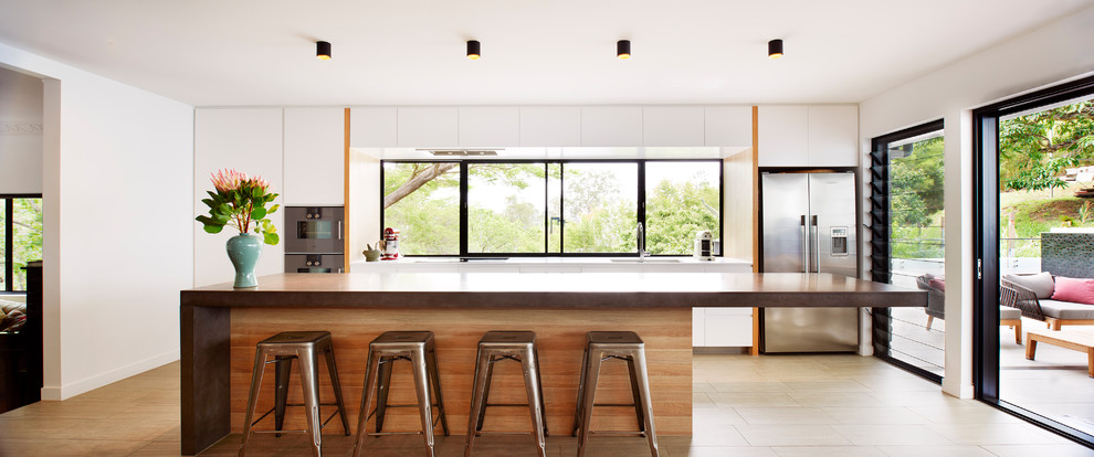 Photo of a large contemporary galley eat-in kitchen in Brisbane with an undermount sink, white cabinets, concrete benchtops, window splashback, stainless steel appliances, with island and beige floor.