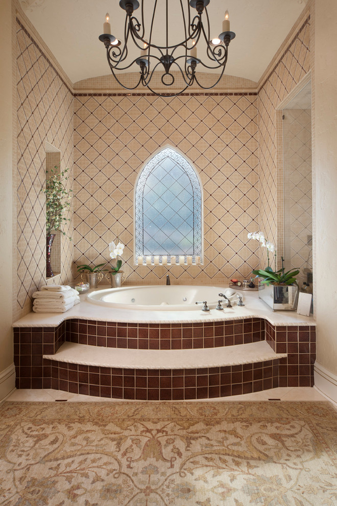 Inspiration for a mediterranean bathroom in Tampa with a drop-in tub and brown tile.