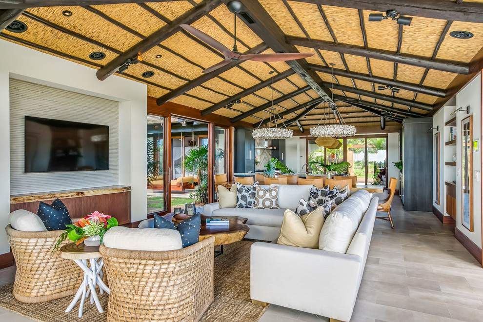 This is an example of a tropical open concept living room in Hawaii with white walls and grey floor.